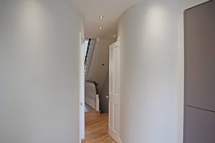 The use of curved walls to connect spaces and keep the living flow. Note the under stairs cupboard is removed to open up the space.