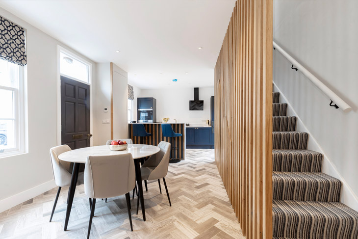 Kitchen, dining area and stairs of newly refurbished victorian terrace house in Cheltenham, Gloucestershire. Featuring full height oak batten screen which conceal hidden understair storage.