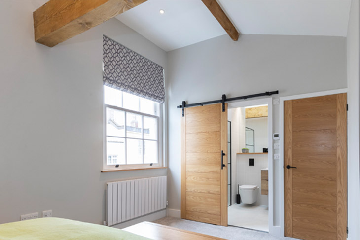 Main bedroom, featuring sliding barn style door to the ensuite, in a newly restored Victorian terraced house in Cheltenham.