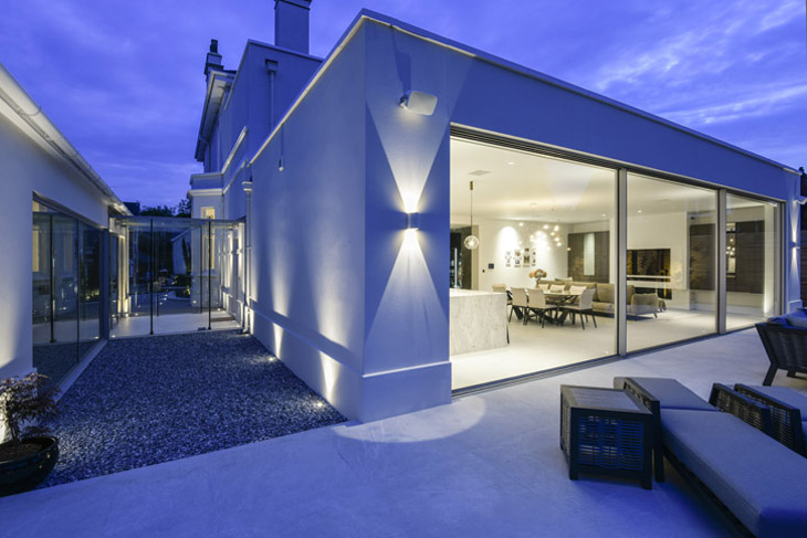 Contemporary extension with large sliding, glass doors to Georgian property. Night shot.
