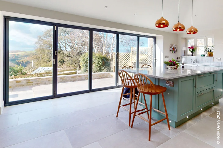 A bright, airy kitchen with expansive bifold doors and tiled floor.