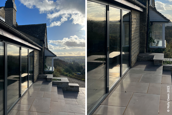 Large bifold windows look over the stunning Cotswolds views with perfectly laid stone flagstone ouder space leading to stairs down into the garden.